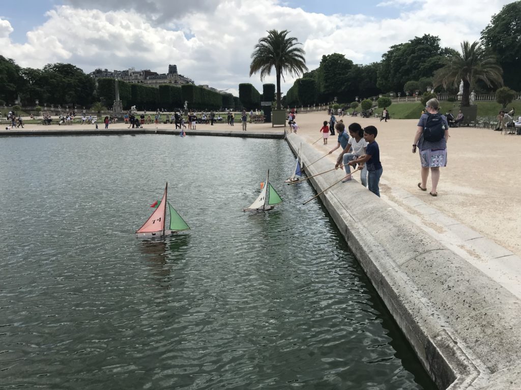 a group of kids playing with toy boats in a lake