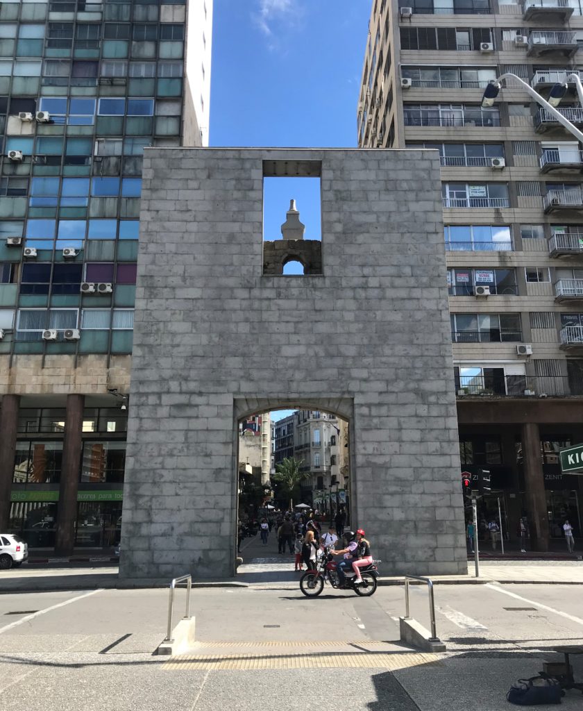 a stone archway with a tower in the middle of a street