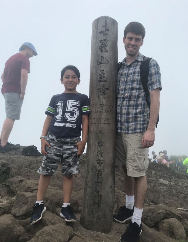 a man and boy standing next to a pole