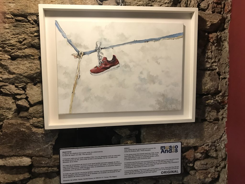 a painting of a shoe from a rope on a brick wall