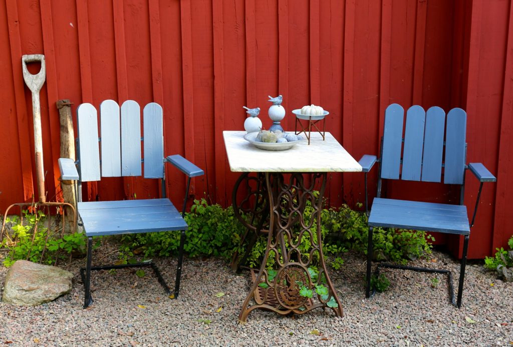 a table and chairs in front of a red fence