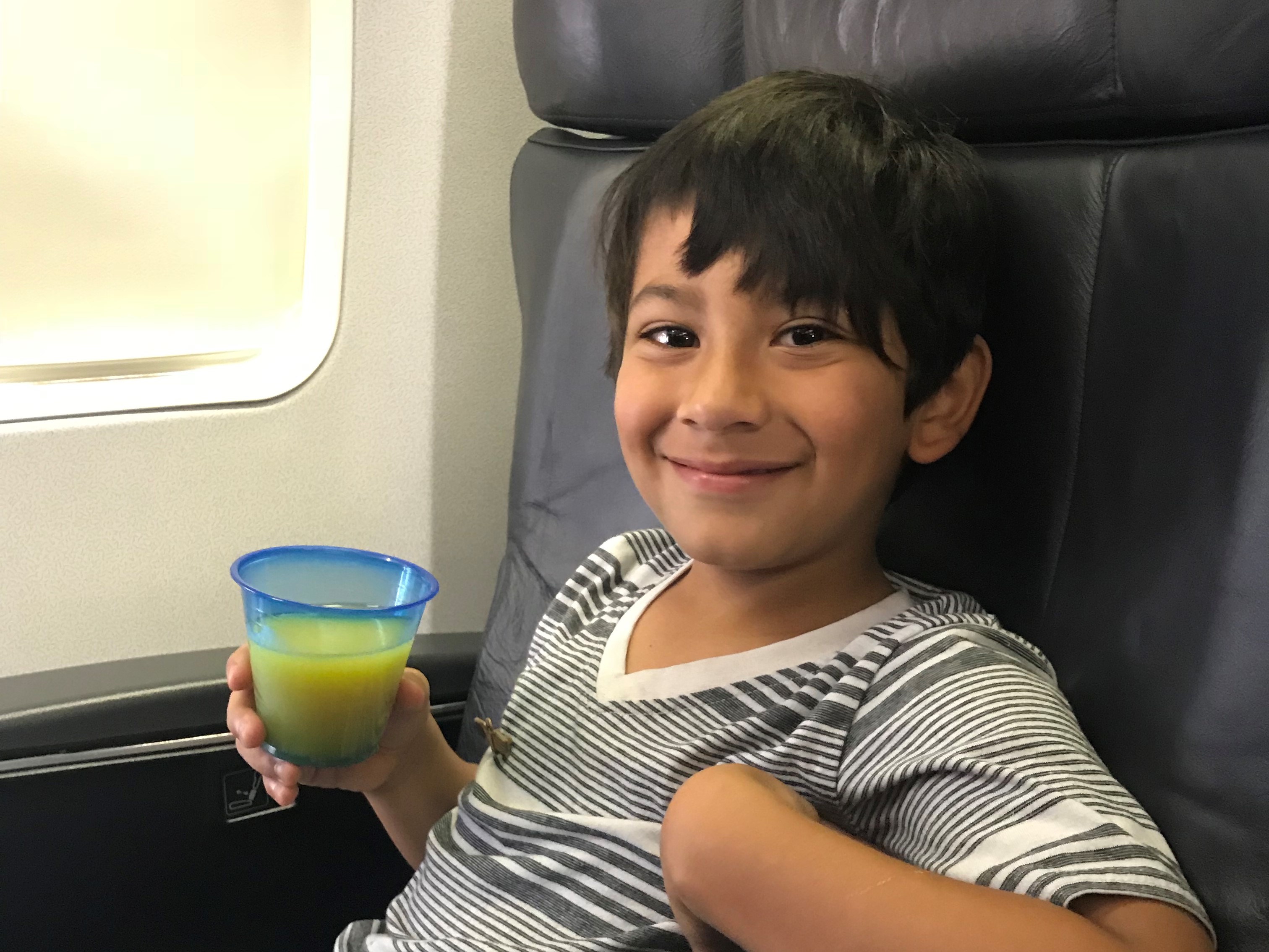 a boy sitting in a chair holding a drink