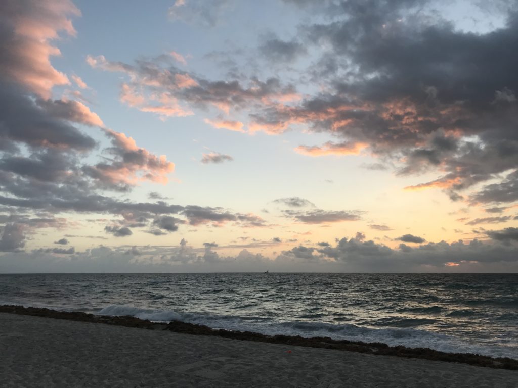 a beach with a body of water and clouds