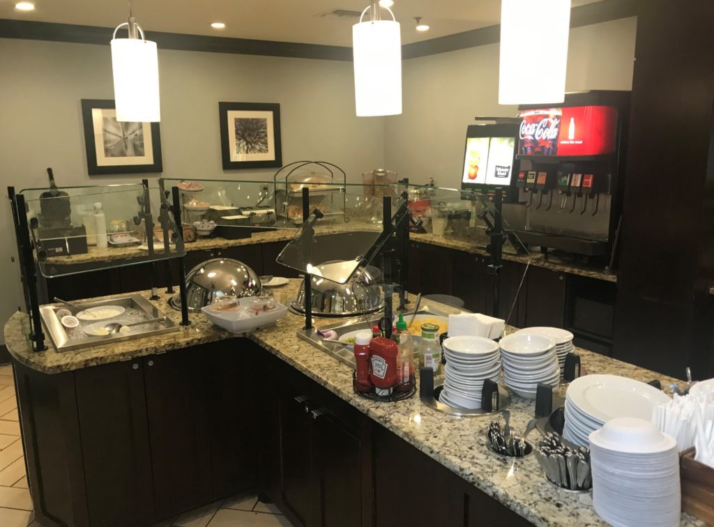 a buffet line with a variety of dishes and a drink dispenser