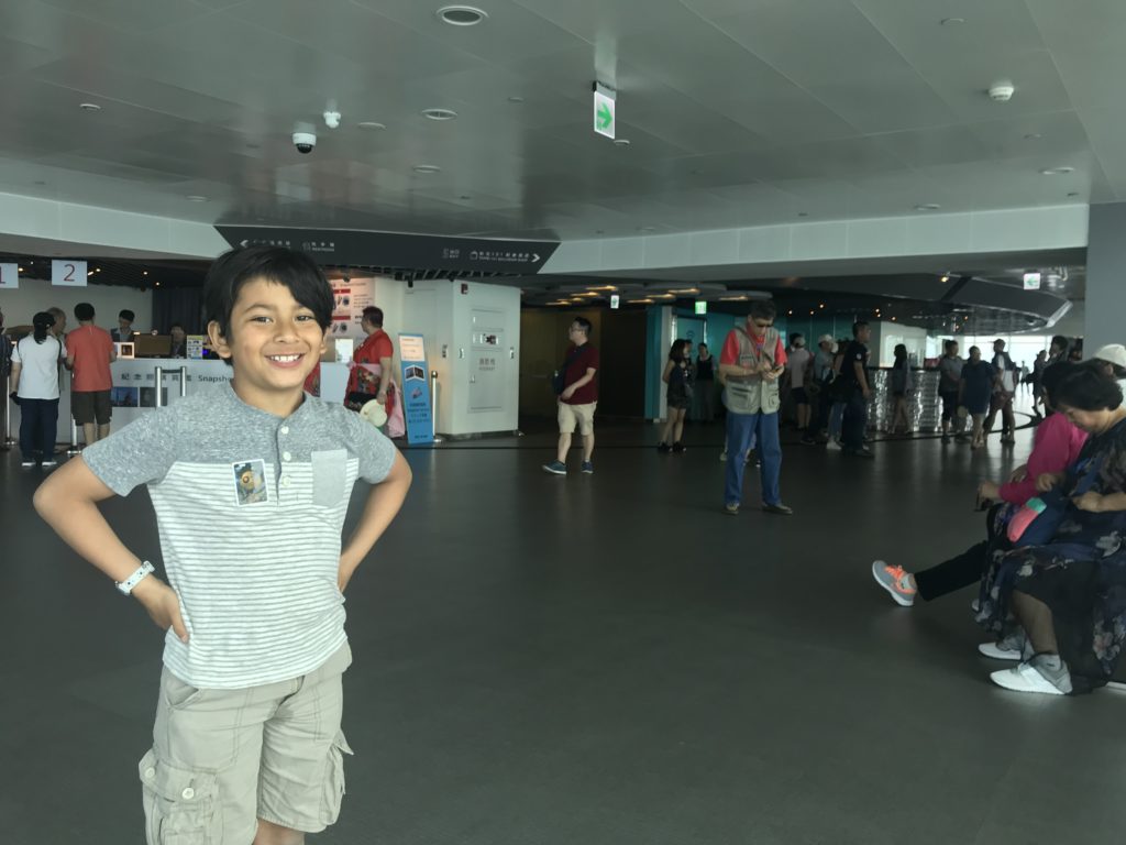a boy standing in a room with people around him