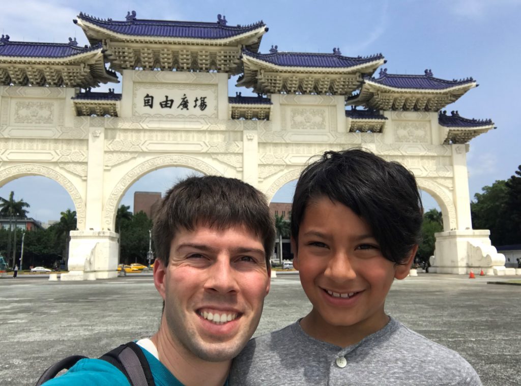 a man and boy posing for a picture in front of a building