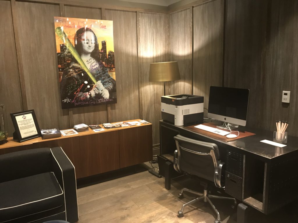a room with a computer desk and a painting on the wall