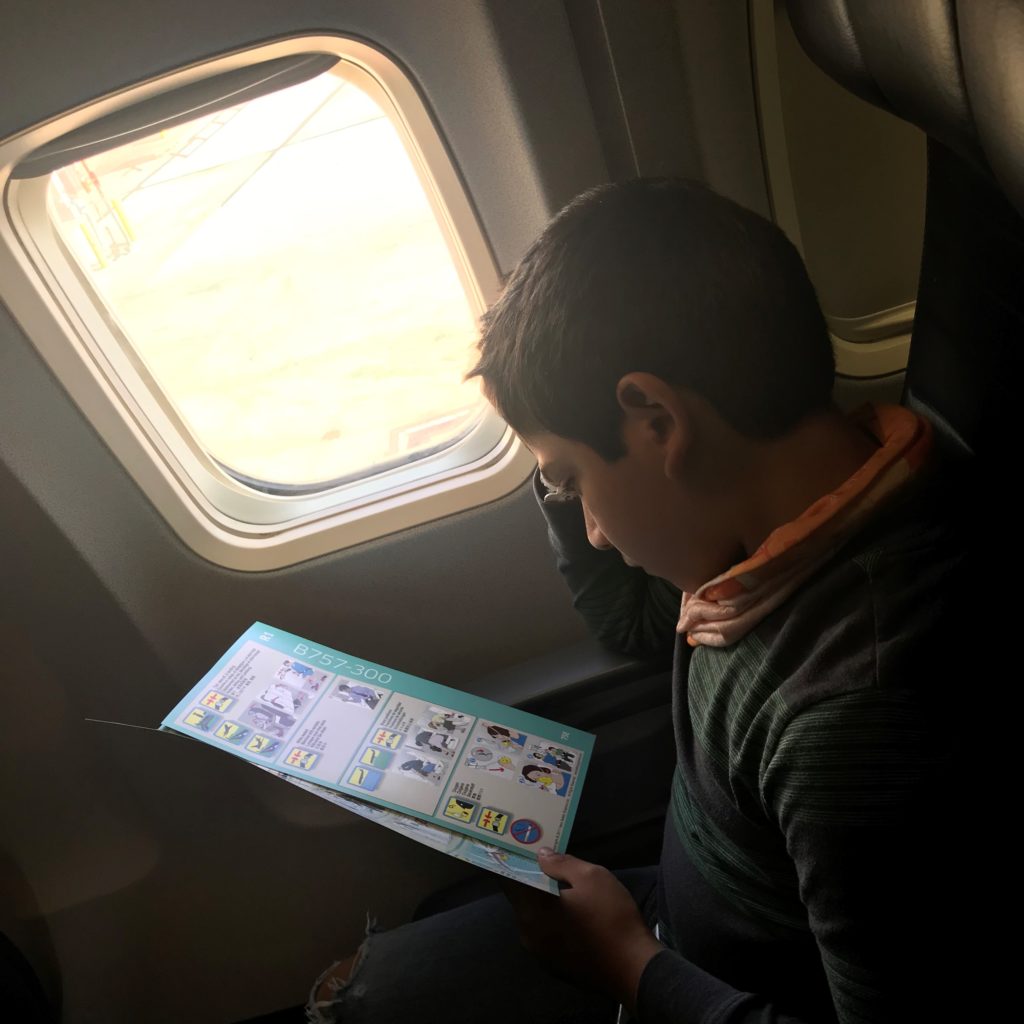 a boy reading a book on an airplane