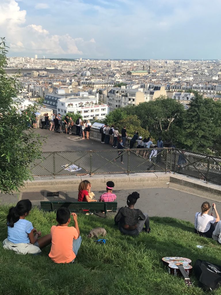 a group of people sitting on a hill overlooking a city