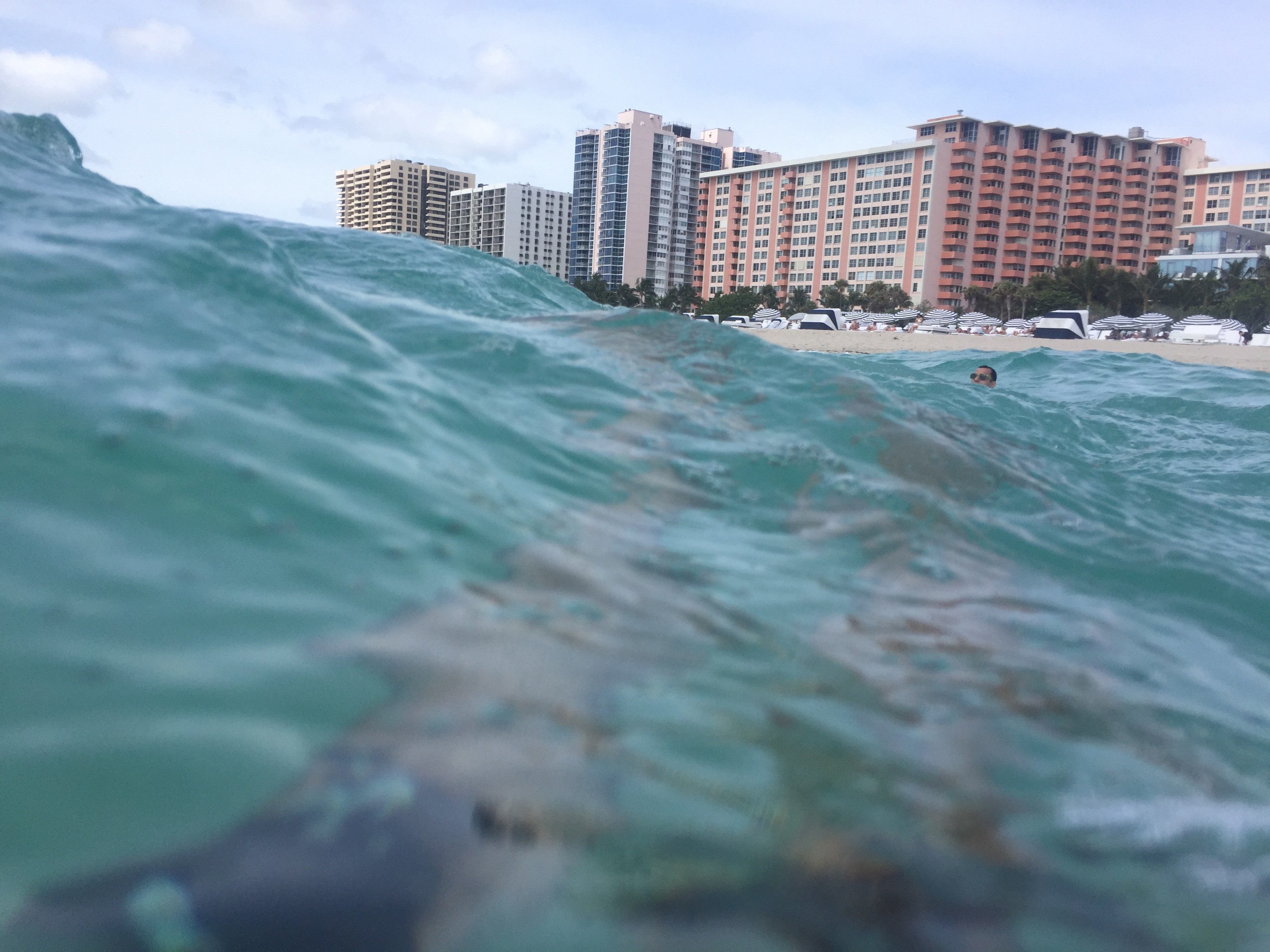 a wave in the water with buildings in the background