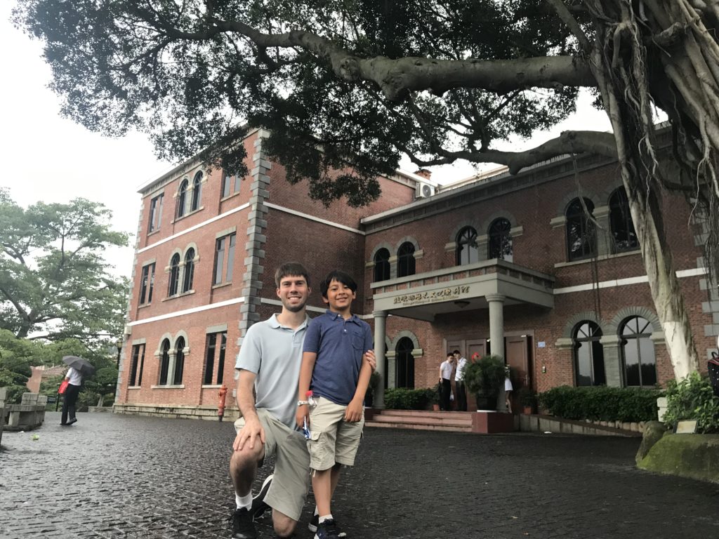 a man and boy posing for a picture in front of a brick building