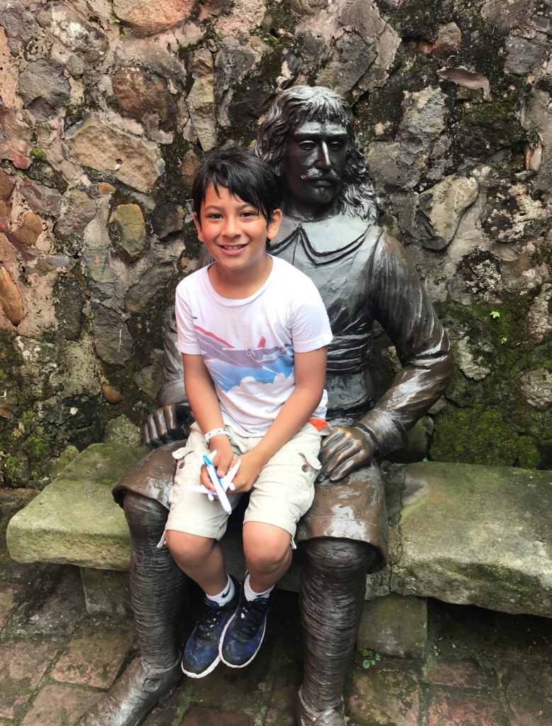 a boy sitting on a statue of a man