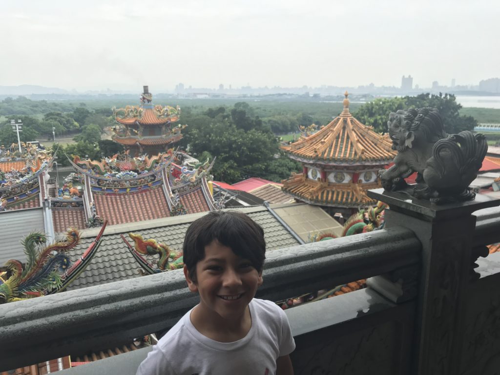 a boy standing on a railing with statues on top of it