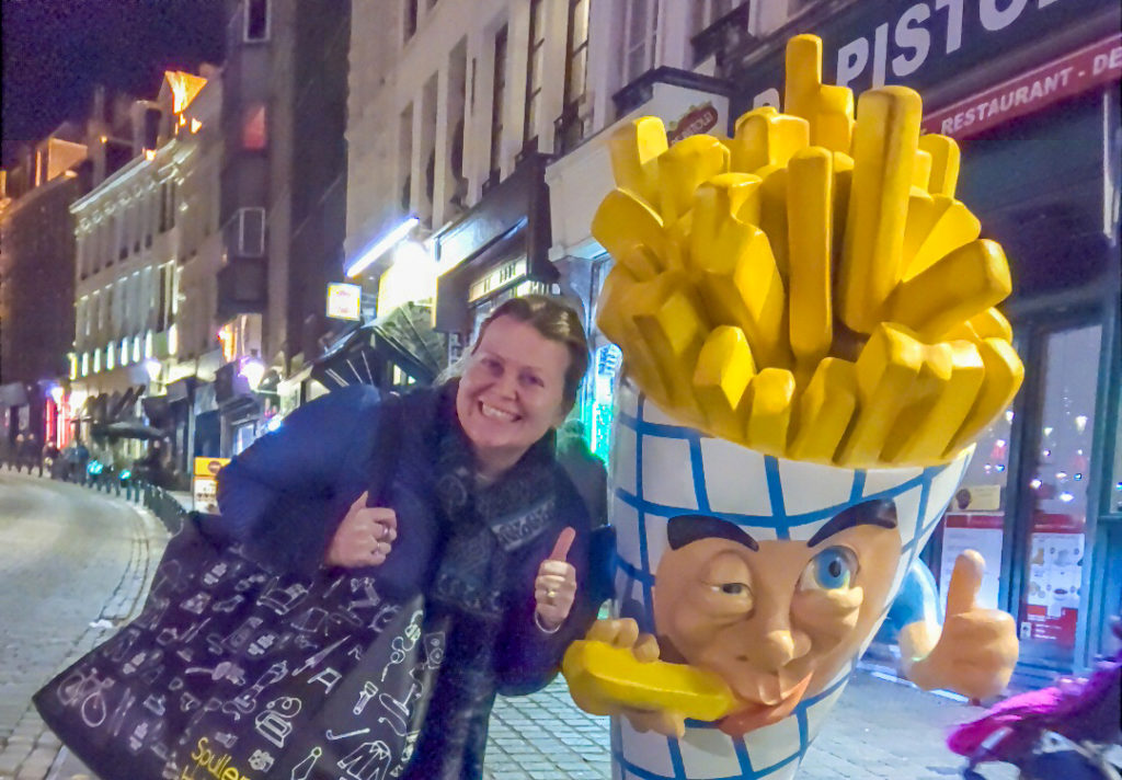 a woman posing with a large french fries statue