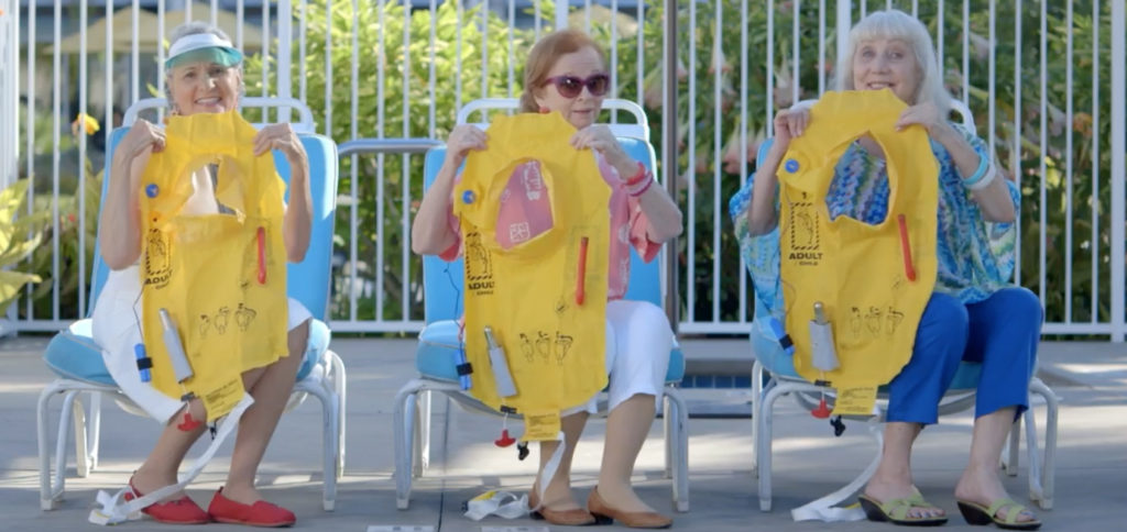 a group of women sitting in chairs holding yellow life vests
