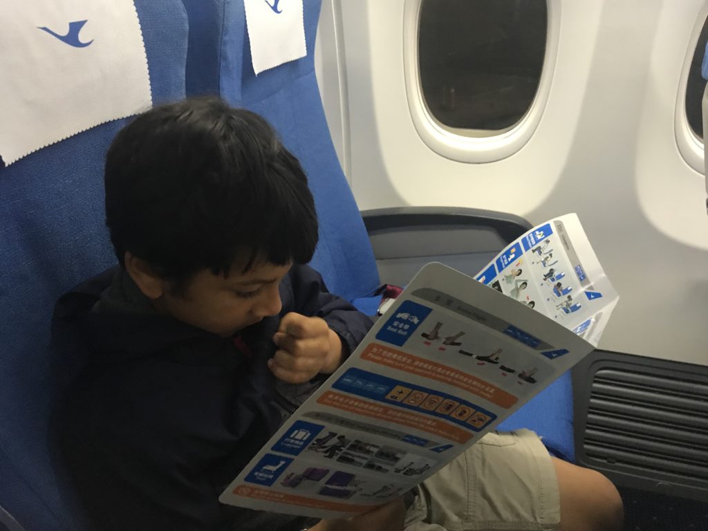 a boy sitting on an airplane reading a book