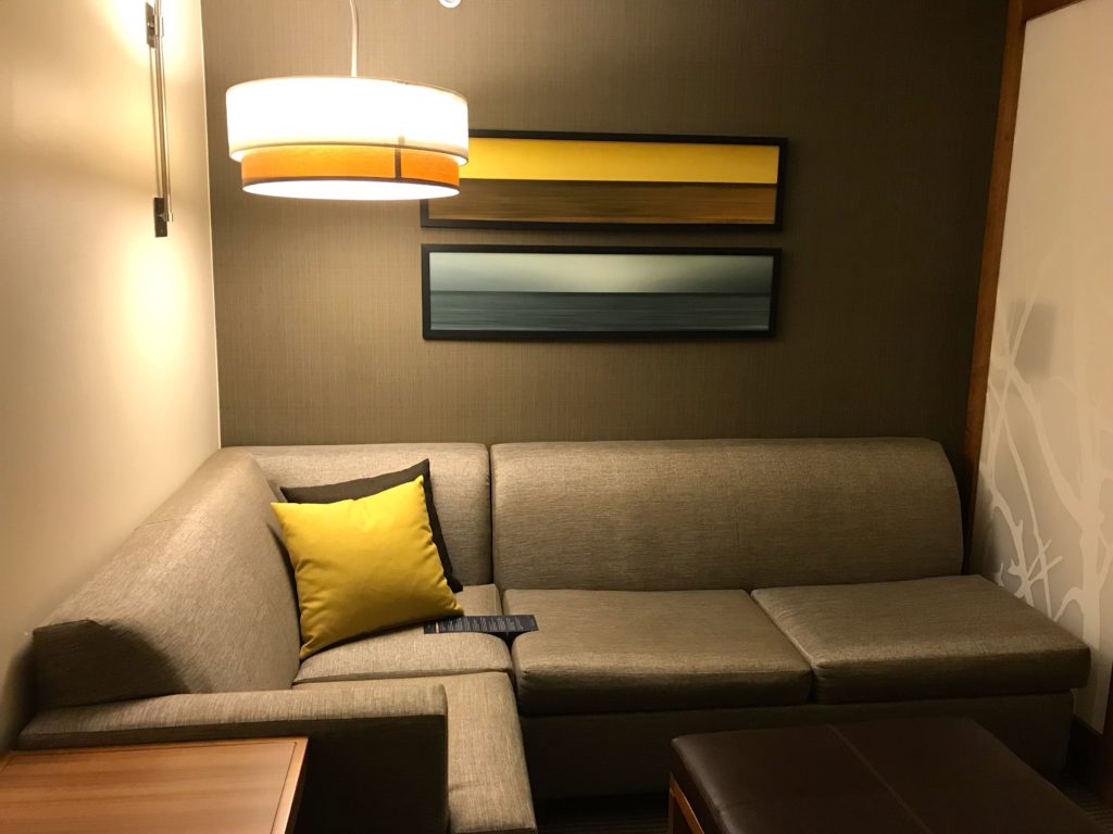 a couch with a yellow pillow and a lamp