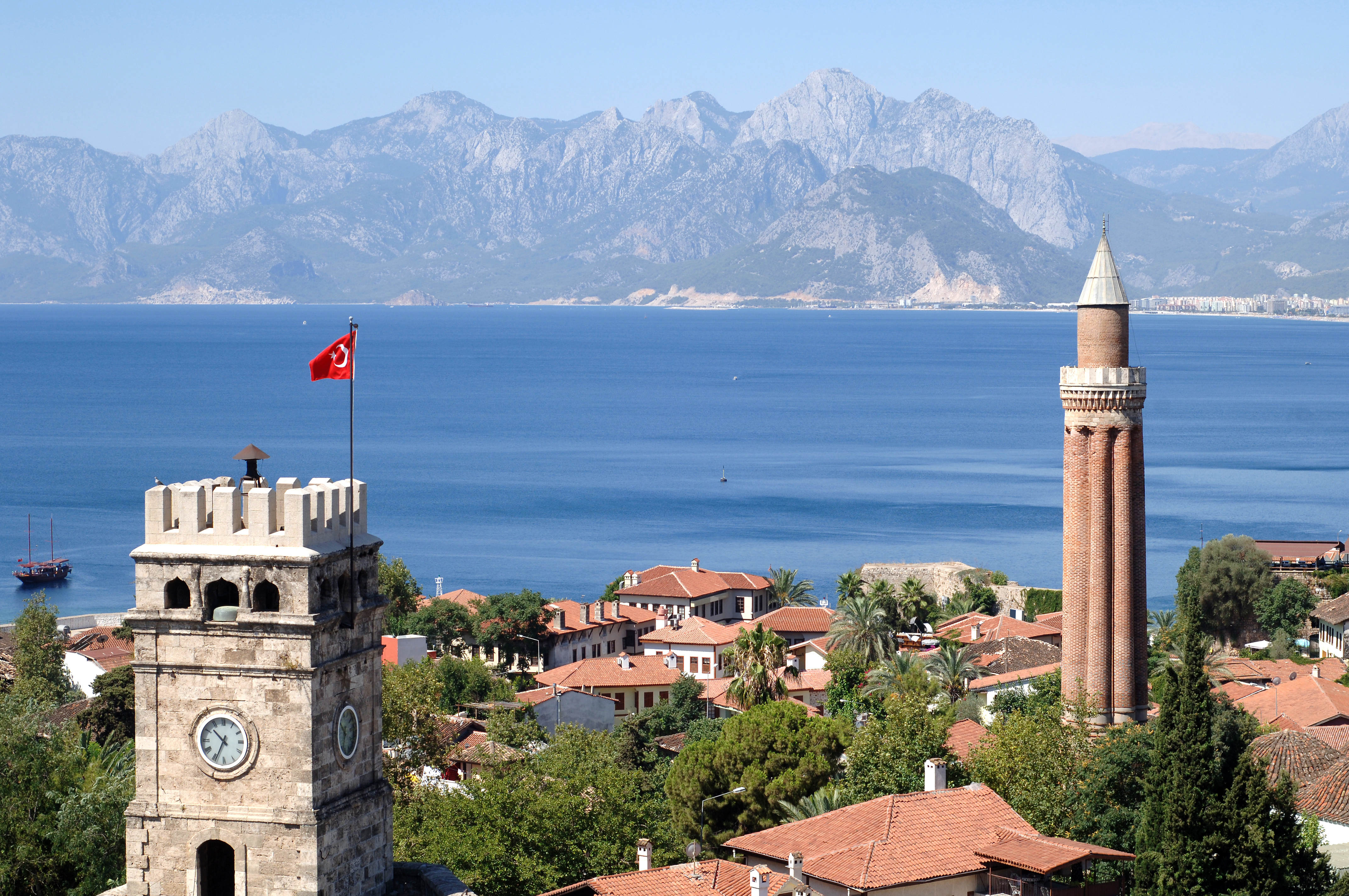 a tower with a flag on top of it and a body of water with mountains in the background