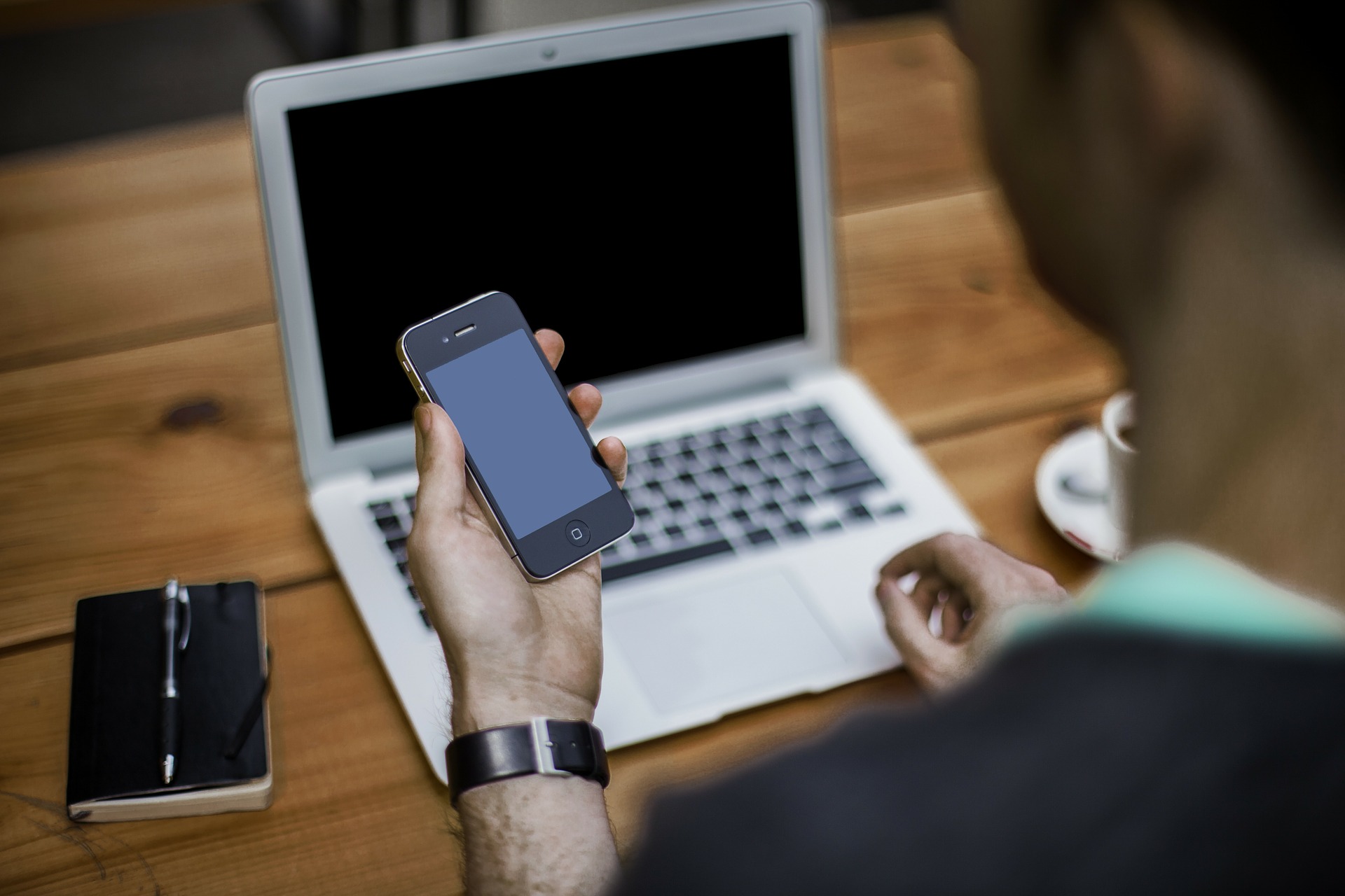 a person holding a phone in front of a laptop