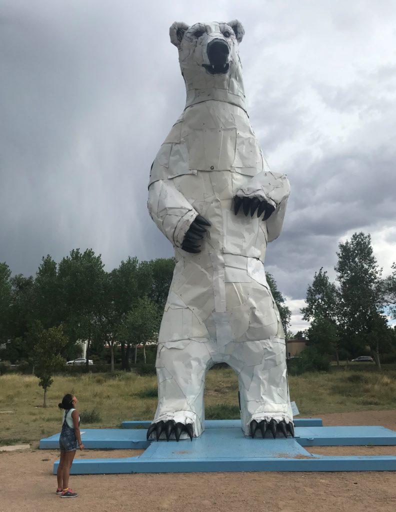 a person standing in front of a large white bear statue