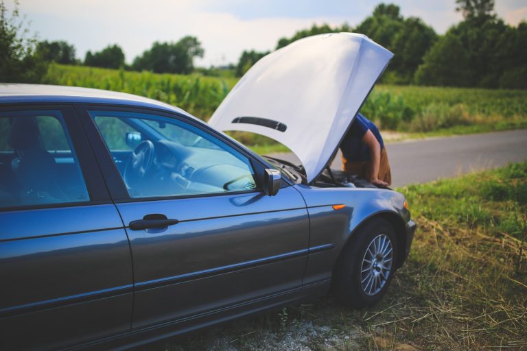 a man looking at the hood of a car