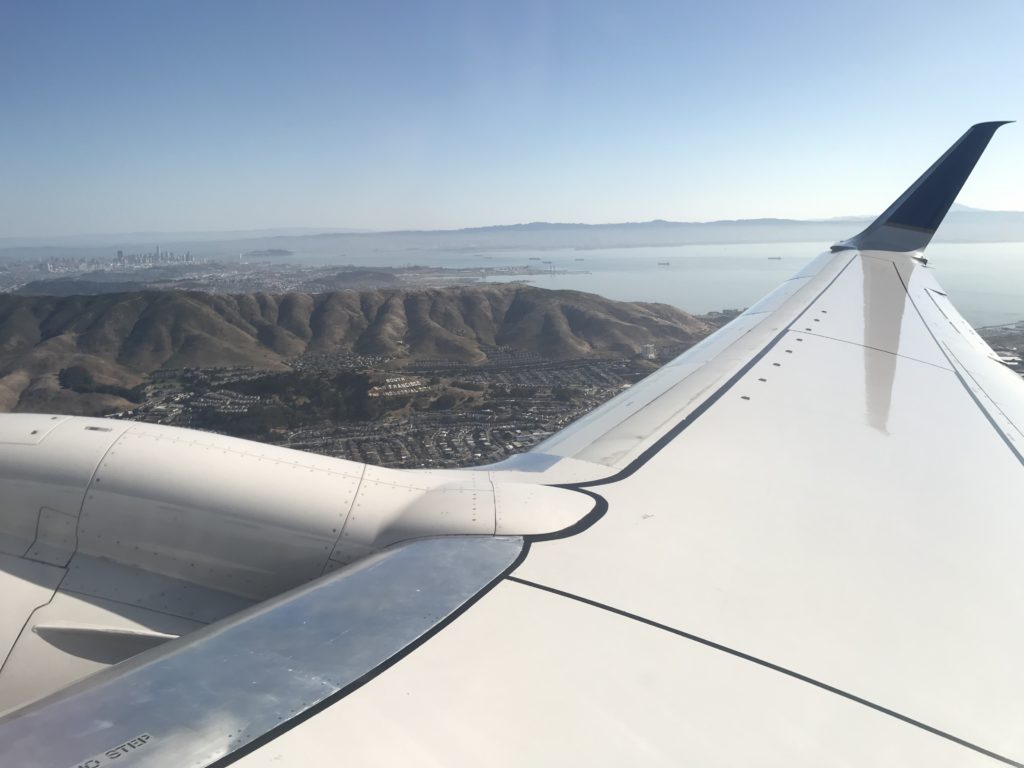 an airplane wing with land and water in the background