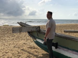 a man standing next to a boat on a beach