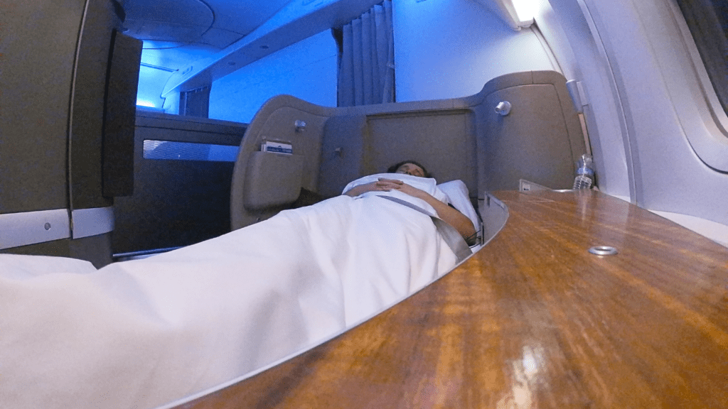 A passenger in Cathay Pacific first class laying in the fully lie-flat bed