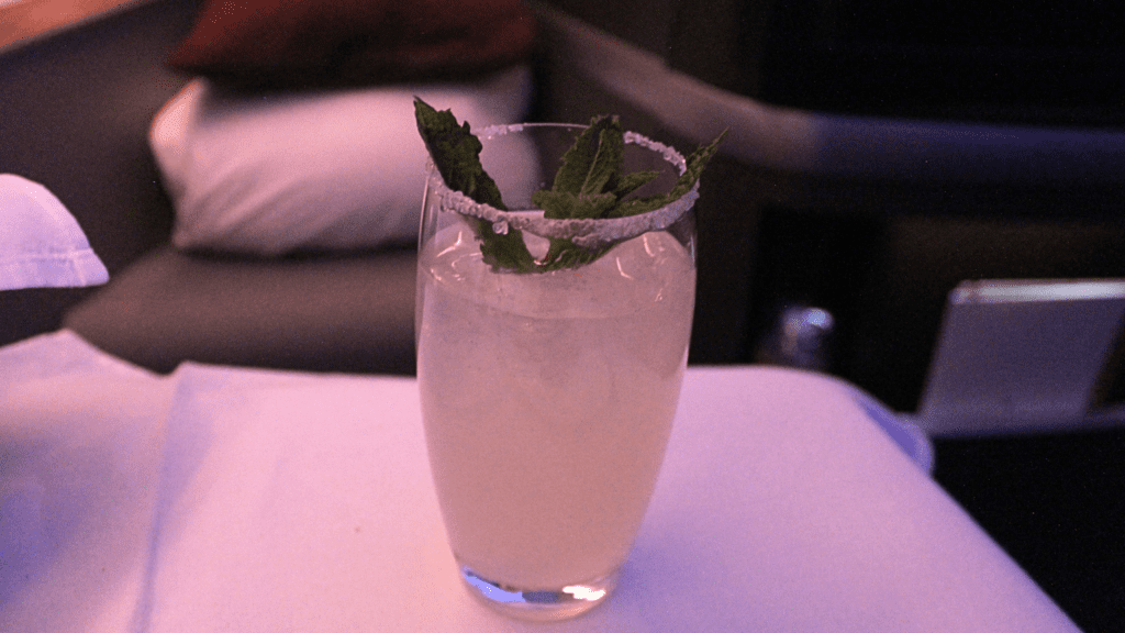 A glass with a cocktail, the Cloud9, garnished with mint leaf.