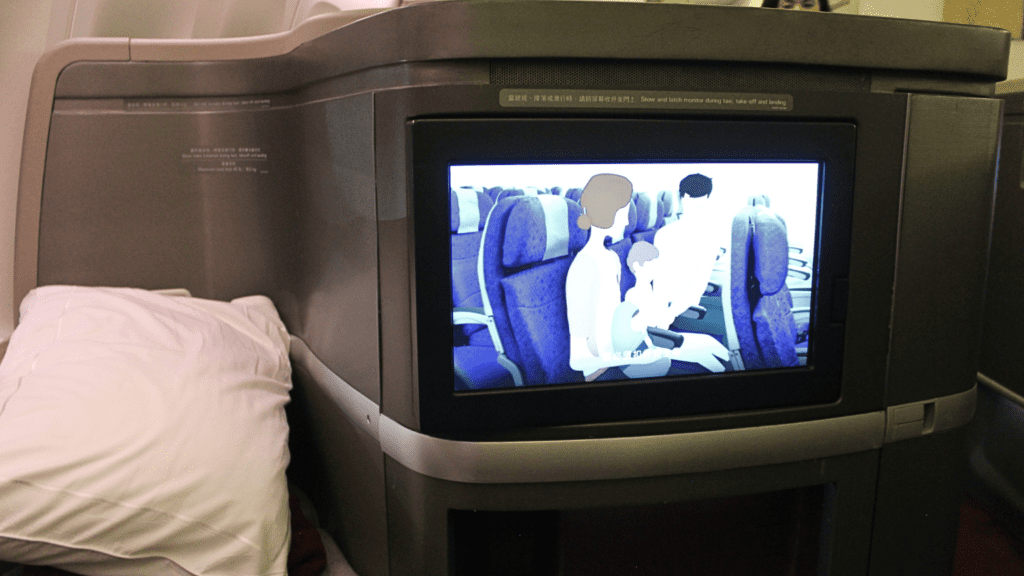 Cathay Pacific first class seatback screen showing safety demonstration video