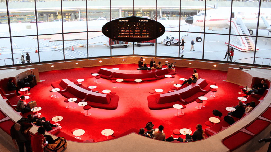 a group of people sitting in a circular area with red tables and chairs