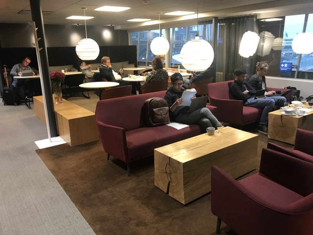 a group of people sitting on couches in a room with tables and chairs