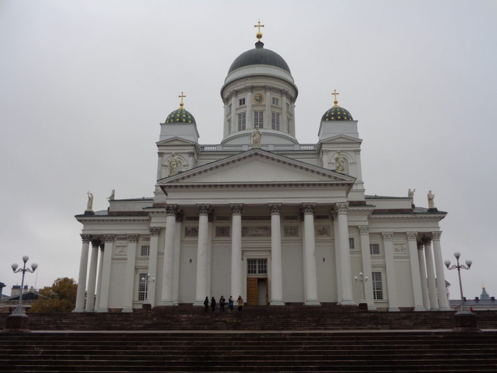 a white building with a dome and a group of people standing on the steps