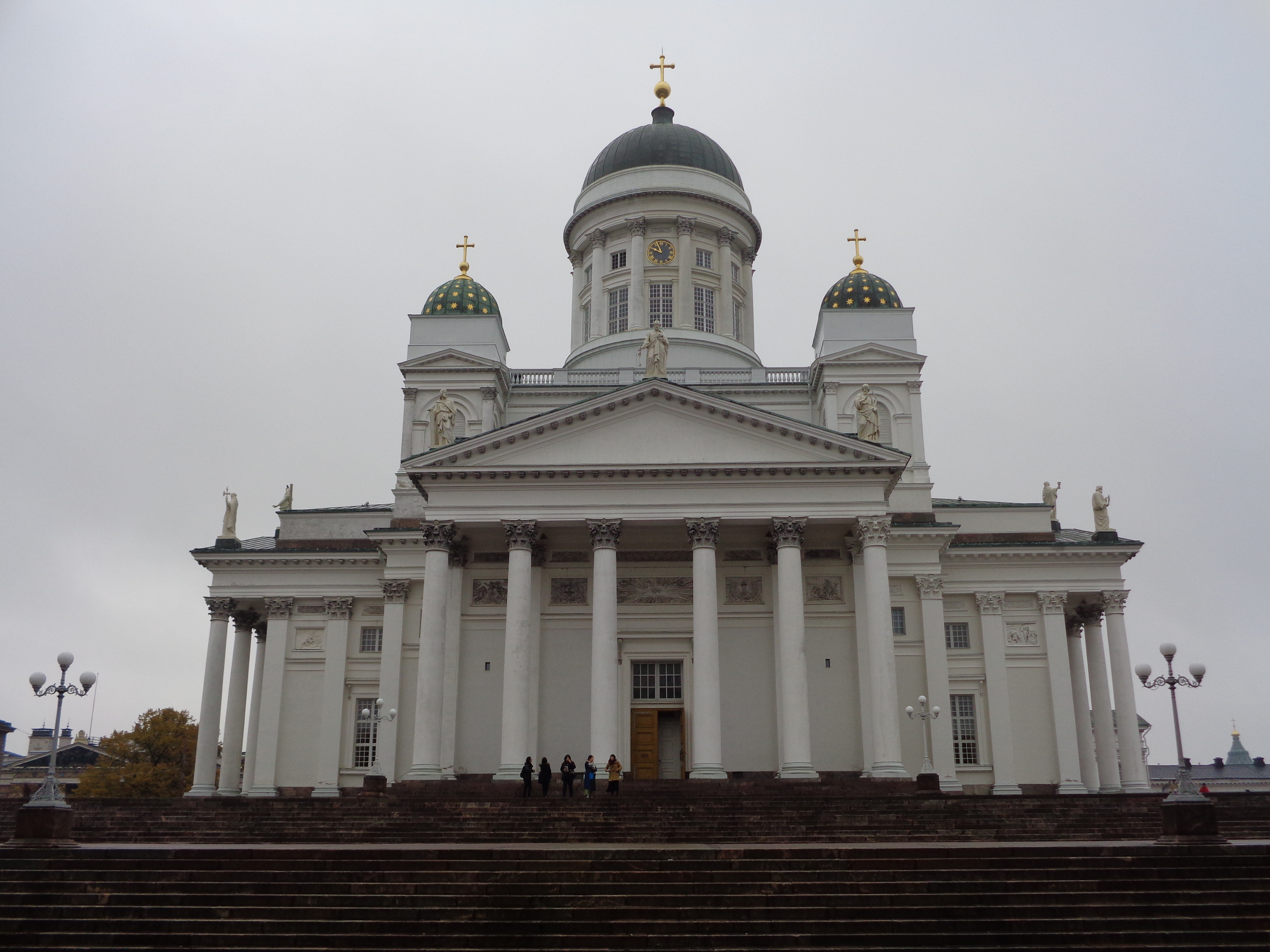 a white building with a dome and a group of people standing on the steps