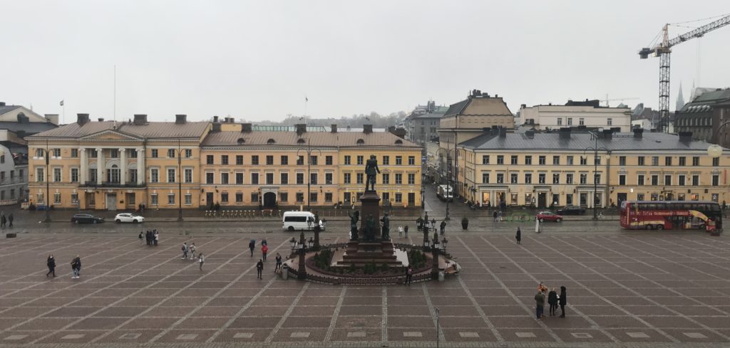 a group of people walking around a square with a statue in the middle
