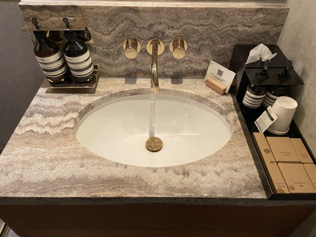 a sink with a gold faucet and soaps