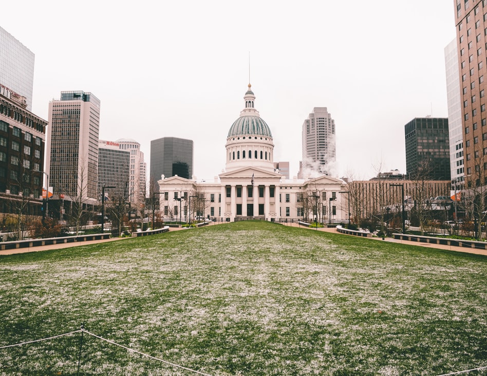 a large white building with a dome and a green lawn in front of it