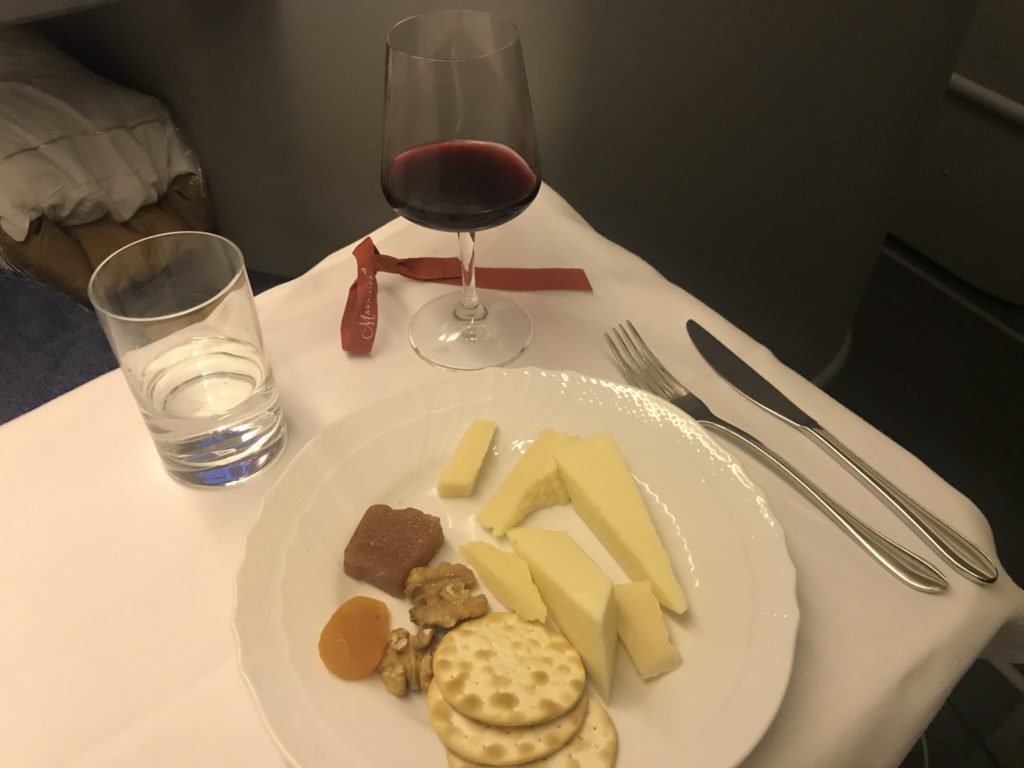 a plate of cheese and crackers with a glass of wine