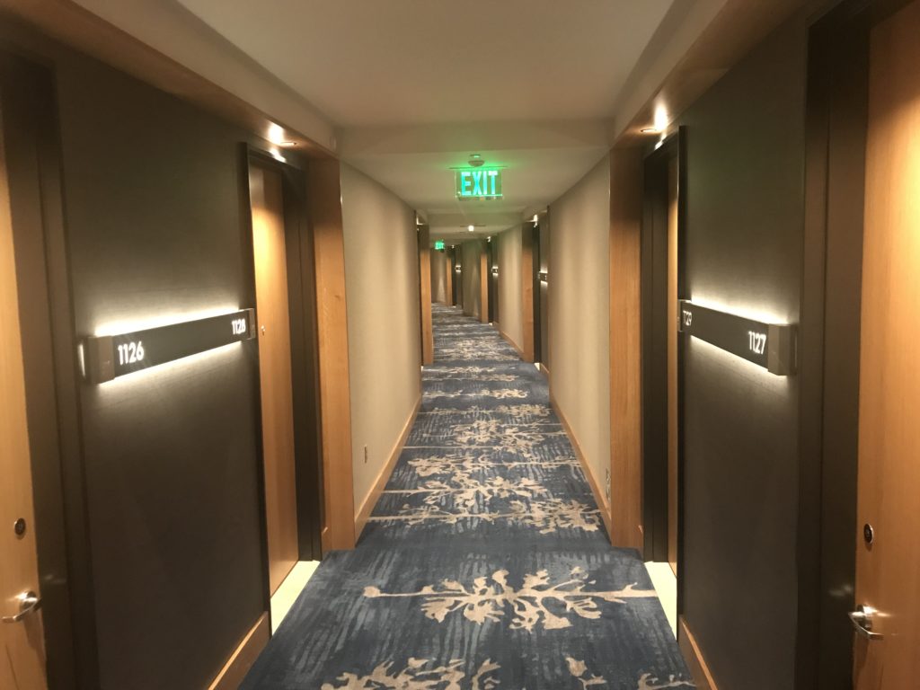 a hallway with a blue carpet and a green sign