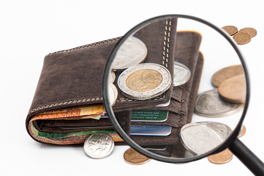 a magnifying glass over a wallet with coins
