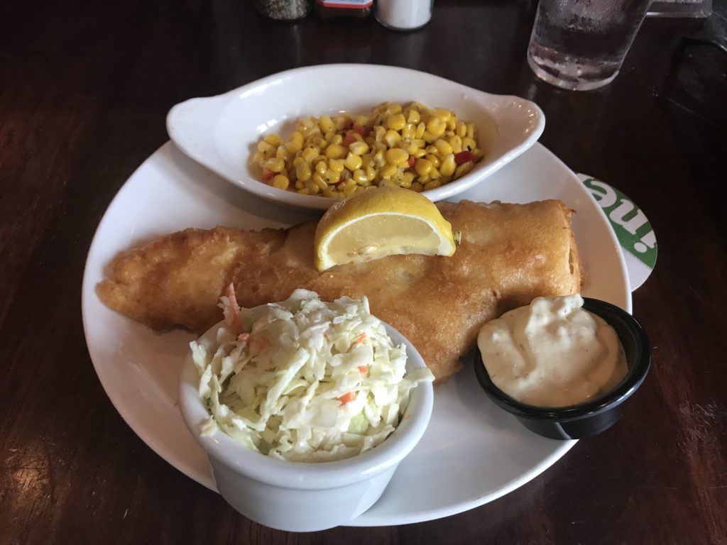a plate of food with a side of corn and a lemon wedge