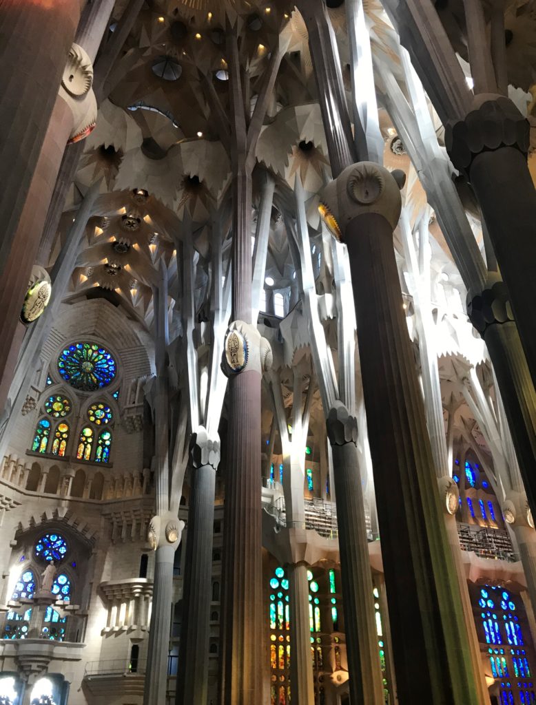 a large building with many columns and stained glass windows with Sagrada Família in the background