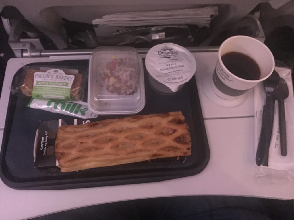 food on a tray with a cup of coffee and a phone