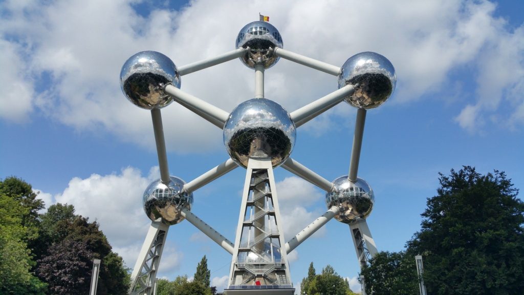 a large metal structure with many spheres with Atomium in the background
