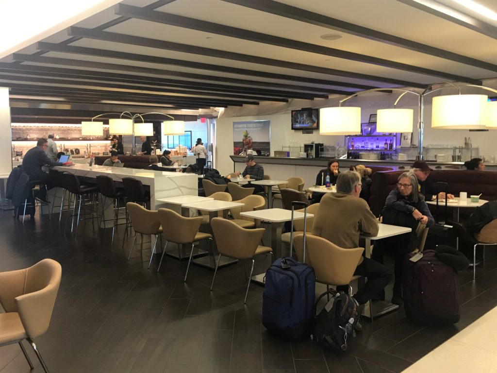 a group of people sitting at tables in a room with luggage