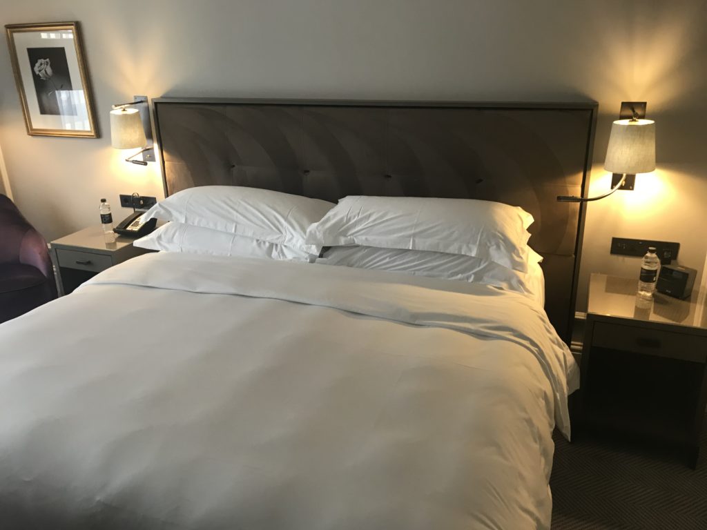 a bed with pillows and a lamp on the side