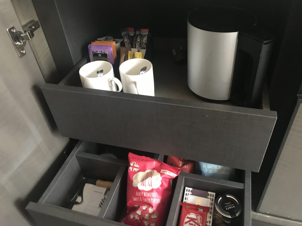a drawer with coffee mugs and snacks