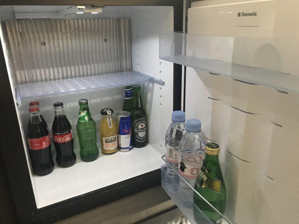 a refrigerator with bottles of soda and a small refrigerator