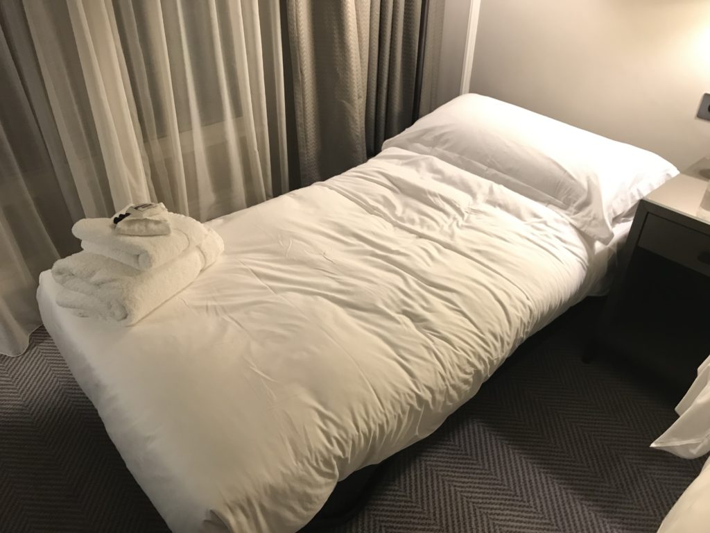 a bed with a white blanket and towels on it