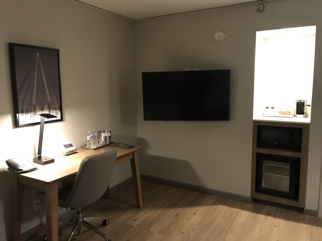 a room with a desk and a television on the wall